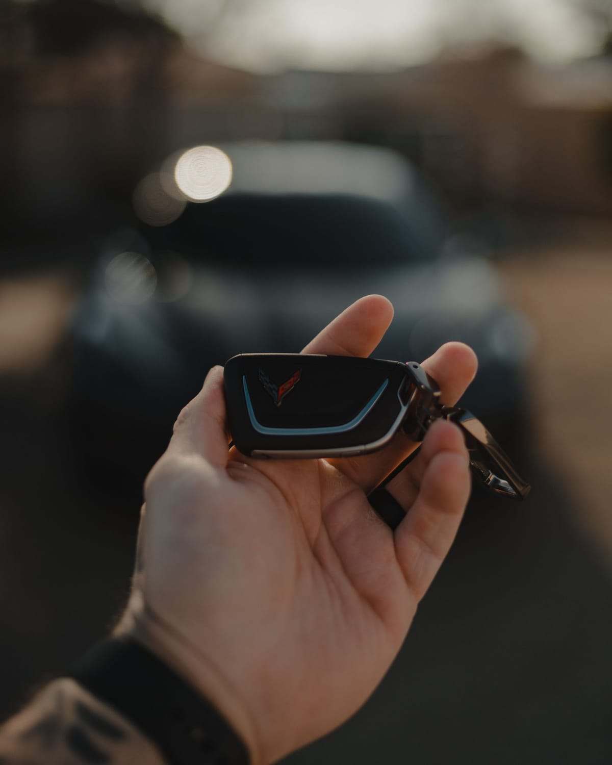 A hand holding the key fob of a new car