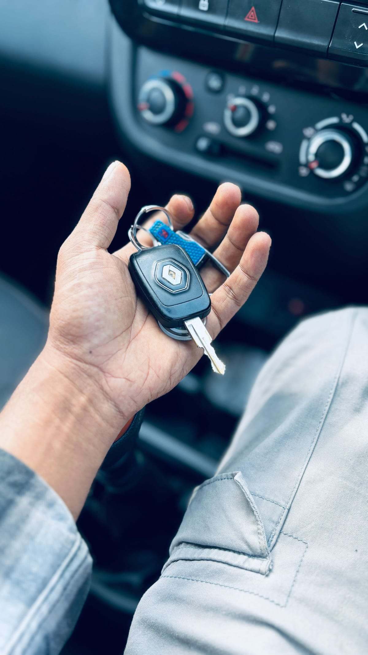 A driver holding the keys to their car, seen from the driver seat