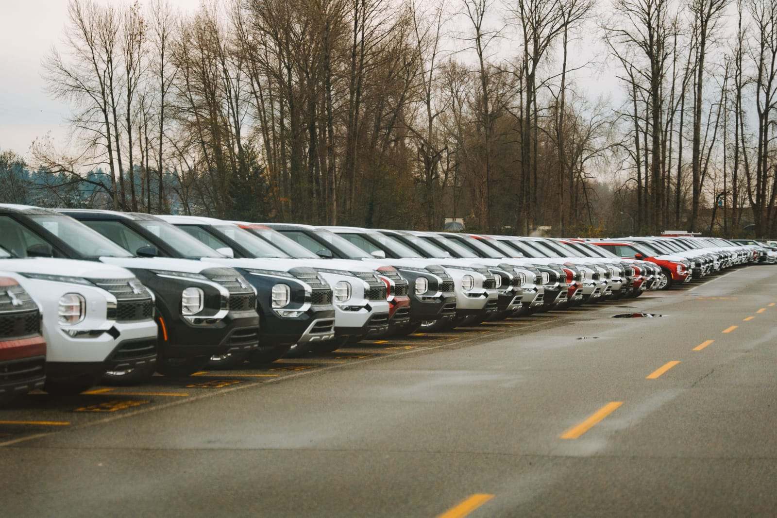 A long row of new SUVs on a dealership lot on an overcast day